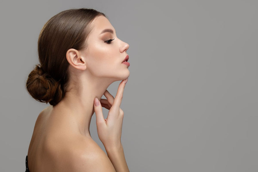 profile of a beautiful young woman  touching her smooth skon on neck and chin 
