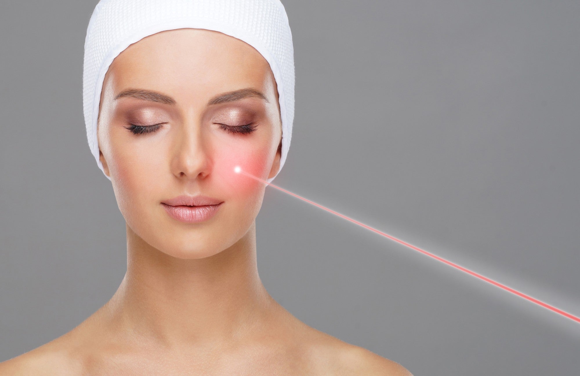 Portret młodej kobiety. Lekarz usuwa naczyniowe znamię za pomocą lasera.